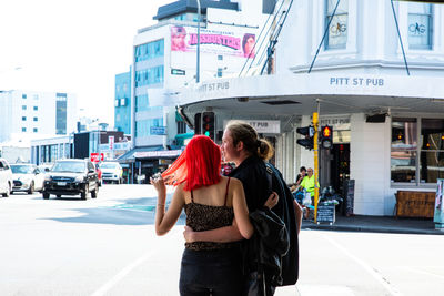 Rear view of friends standing on road in city