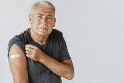 Portrait of senior man standing against white background