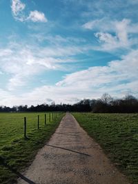 Footpath amidst field against sky