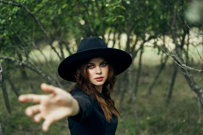 Young woman wearing hat standing against trees