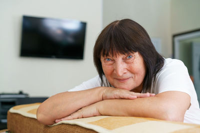 Older grandmother is sitting on cozy sofa in living room. happy mature woman