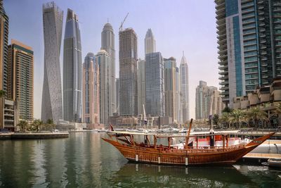 Modern buildings by river against sky in city