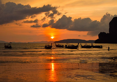 Silhouette longtail boats on sea against sky during sunset