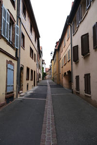 Empty road amidst buildings against sky