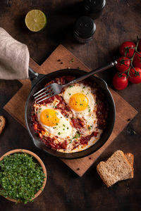 Breakfast with shakshouka and vegetables on a wooden table close up image