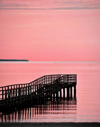 Pier over sea against sky during sunset