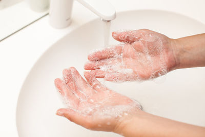 Cropped hands of woman washing in sink