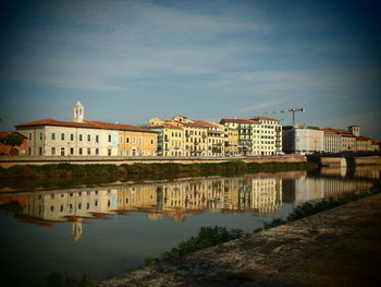 Buildings by river against sky in city