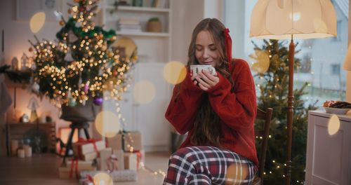 Young woman holding christmas tree at home