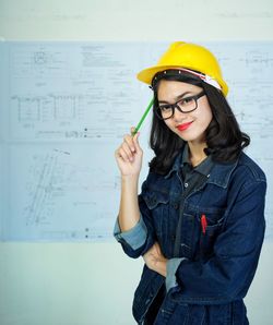 Portrait of young woman standing against wall