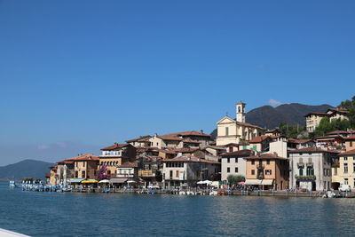 Buildings by sea against blue sky