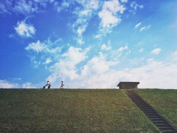 People on field against cloudy sky