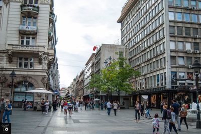 People walking on street amidst buildings in city