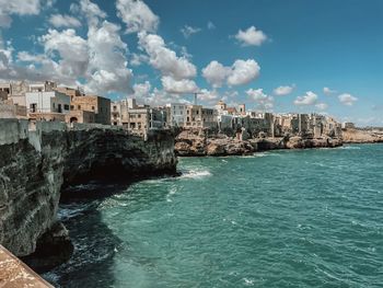 Buildings by sea against sky