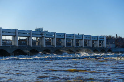 Sea by building against clear blue sky