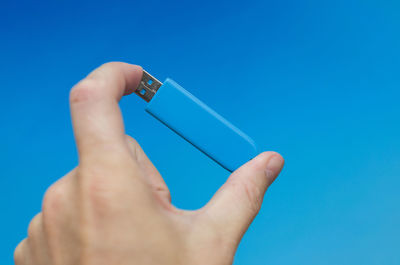 Close-up of hand holding blue background