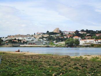 View of city by river against sky