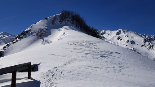 Scenic view of snow covered mountains against clear blue sky