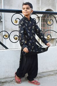 Portrait of smiling woman standing against railing