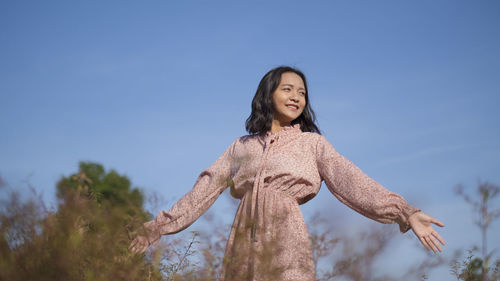 Low angle portrait of woman against blue sky