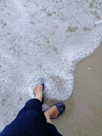 Low section of man standing on beach