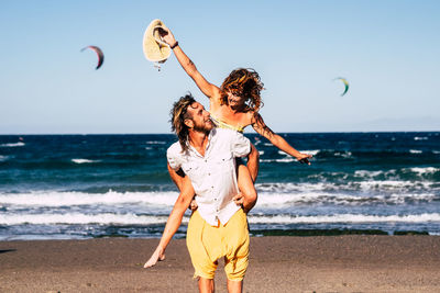 Smiling man carrying girlfriend on back at beach