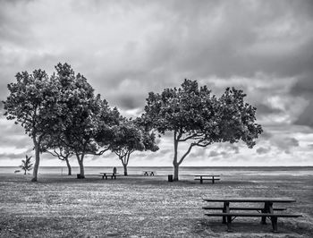 Park bench on field against sky