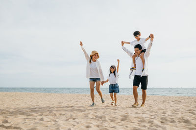 Rear view of woman with arms outstretched standing at beach