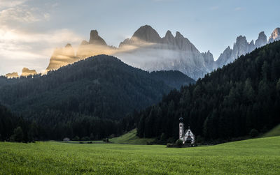 Panoramic view of landscape and mountains against sky with little church 