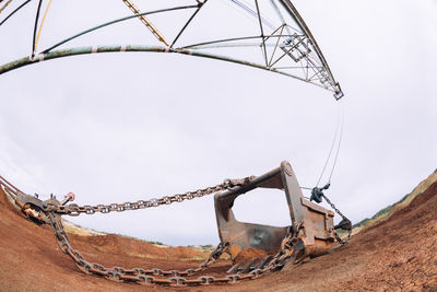 Low angle view of rusty wheel against clear sky