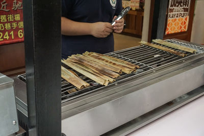 Midsection of man standing on barbecue grill