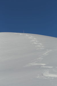 Scenic view of snow covered landscape against clear blue sky