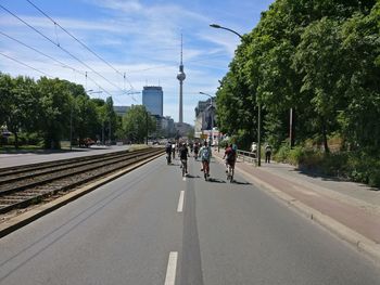 People on railroad track against sky