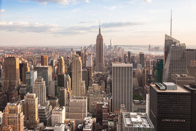 Aerial view of buildings in city against cloudy sky