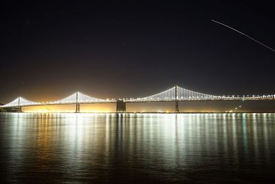 Golden gate bridge over river against clear sky at night