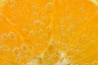 Slice of orange fruit in sparkling water. orange fruit slice covered by bubbles in carbonated water