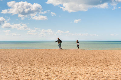 Men standing on beach against sky