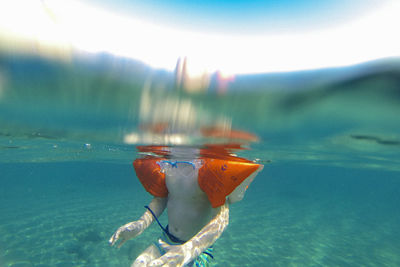 Midsection of boy with water wings swimming in sea