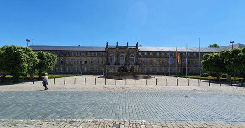 People at historical building against blue sky