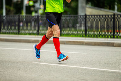 Legs male runner in bright red compression socks run down street race