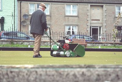 Man working on bowling green mowing the grass