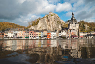 Buildings by river against sky