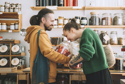 Woman smelling dried strawberries with man holding jar at store