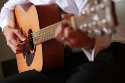 Midsection of man playing guitar