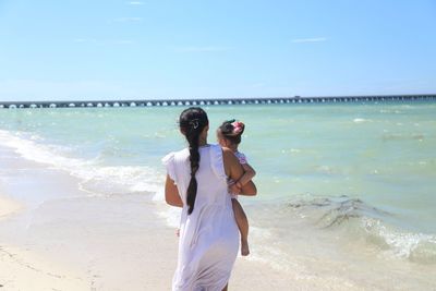Mother and daughter walking in the beach