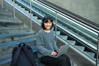 Portrait of young woman standing against building