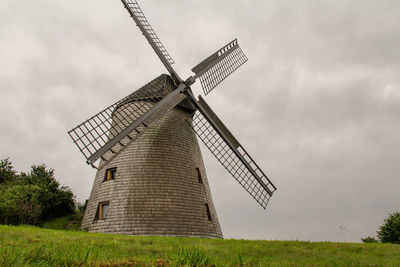 Traditional windmill on field against sky