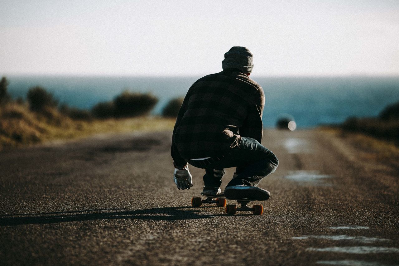 one person, sky, road, full length, real people, casual clothing, men, leisure activity, transportation, nature, sport, rear view, lifestyles, day, sunlight, motion, street, focus on foreground, the way forward, outdoors, diminishing perspective, riding