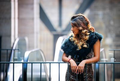 Young woman standing by railing in city