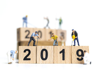 Close-up of human figurines with wooden numbered blocks over white background